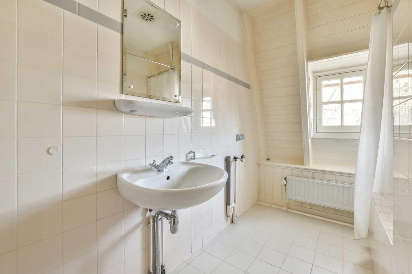 Glass partition between shower tap and wall hung toilet in modern restroom at home